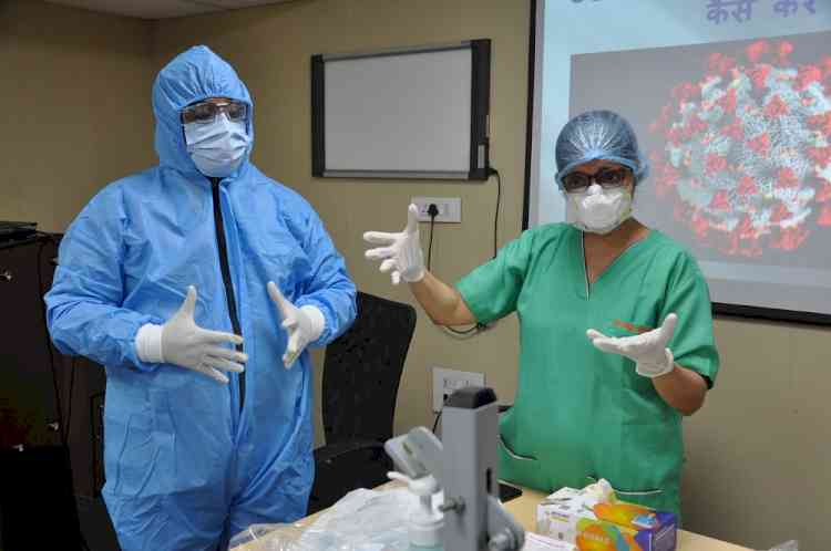 Healthcare workers being given training in donning and doffing of personal protective equipment kit