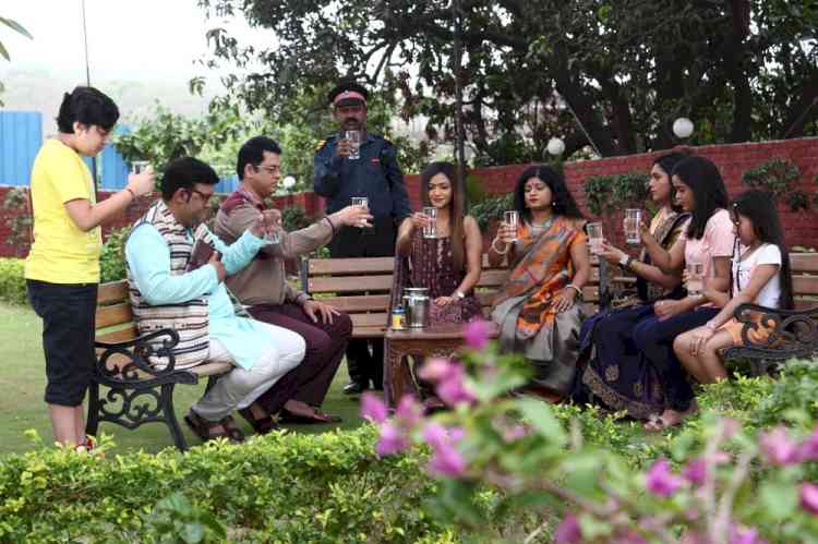 Why is everyone in Sai Dham society holding a glass of water all day?